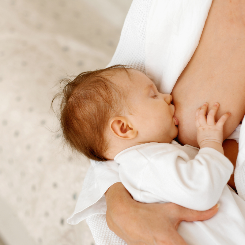 mom breastfeeding baby while wearing white robe