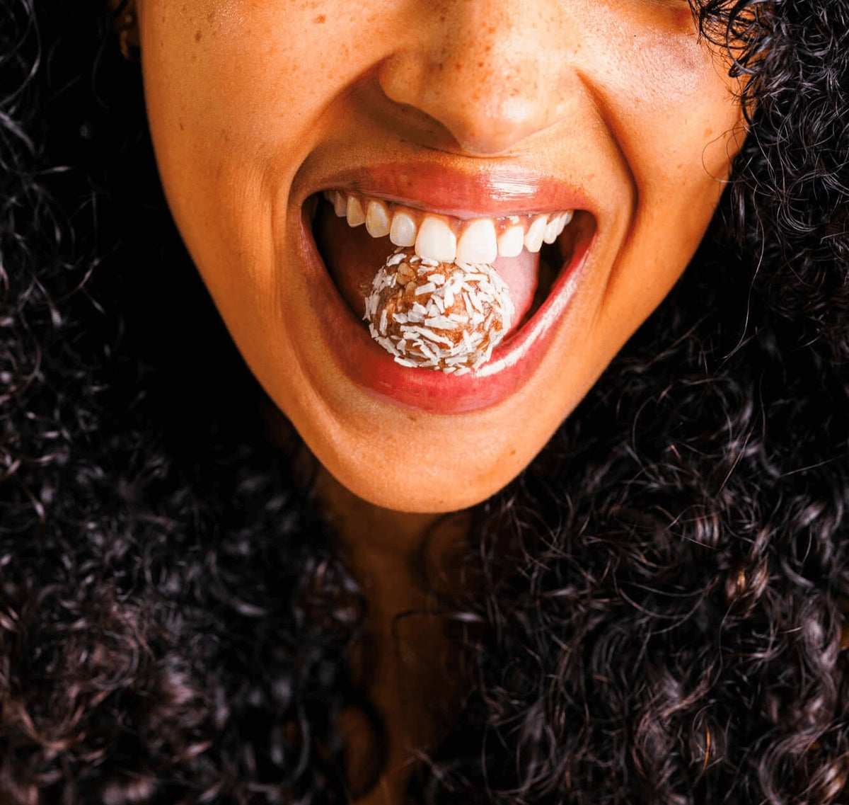 Smiling woman placing a Nunona Mama Bite on her tongue
